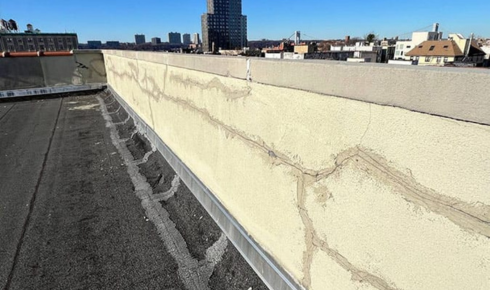 How can checking for cracks along the junction of roof and parapet wall warn you about potential seepage