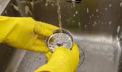 How can using a simple mesh strainer in kitchen sinks prevent food bits from clogging pipes